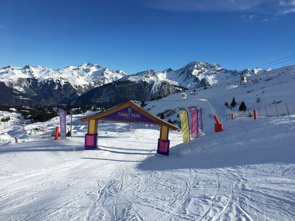 Skiers at the entrance to a Three Valleys piste surrounded by stunning mountain scenery.