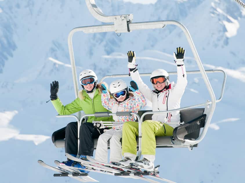 Family enjoying a chairlift ride with stunning mountain views in the Three Valleys ski area.