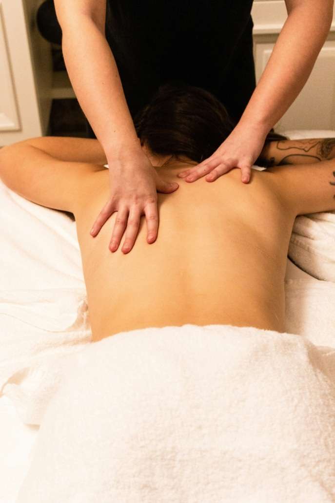 Professional therapist providing a therapeutic back massage treatment in a comfortable chalet setting.