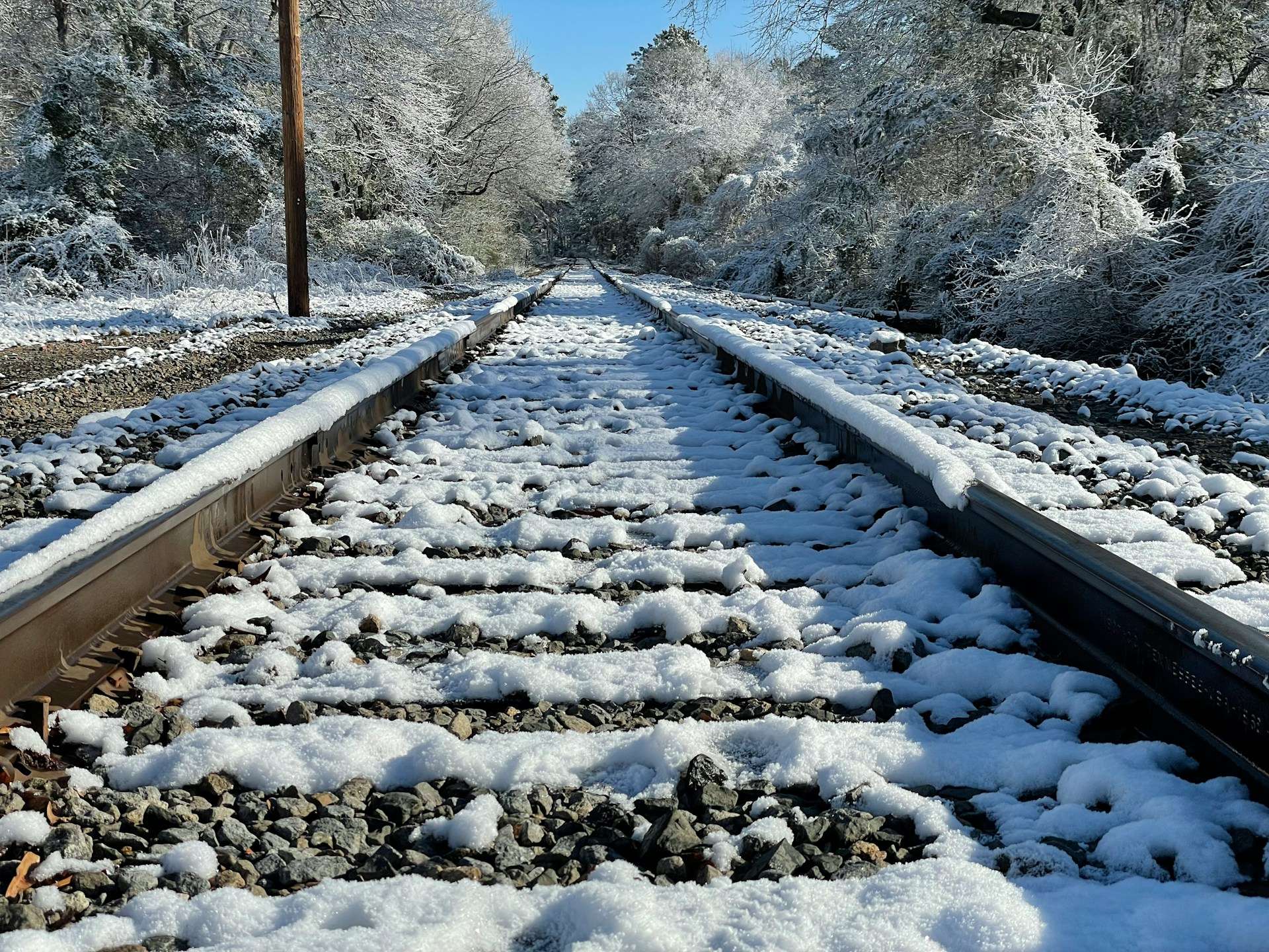 train track covered in snow next to a forest